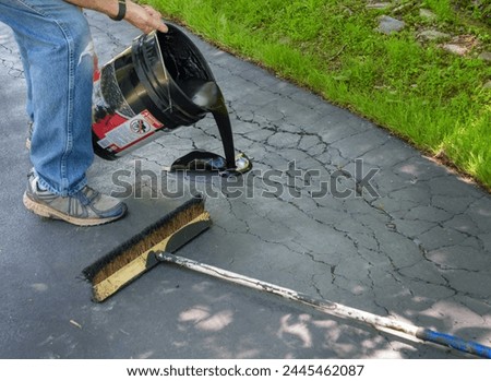 Pouring asphalt sealant on driveway to repair cracks Royalty-Free Stock Photo #2445462087