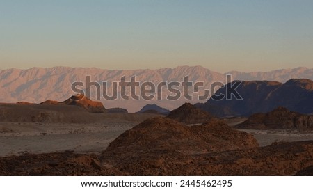The Timna Valley, cast in the warm light of dawn, stands still as ancient mountains watch over this stark yet beautiful Israeli landscape Royalty-Free Stock Photo #2445462495