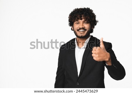 Happy young Indian businessman in black tuxedo showing thumb up isolated over white background. Positive Hindu clerk lawyer manager expressing agreement like