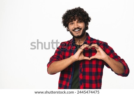 Cheerful young Indian man having romantic mood isolated over white background. Handsome Hindi boy showing heart gesture. Love and relationship concept