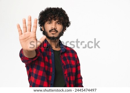 Serious young Hindi man showing stop gesture with palm isolated over white background. Indian handsome boy expressing dismissal gesture, forbidden concept Royalty-Free Stock Photo #2445474497