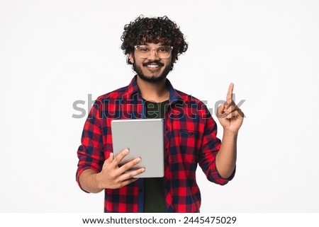 Cheerful young Indian freelancer having idea with digital tablet isolated over white background. Hindi cheerful man creating startup new business online