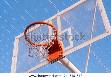 View of the basketball hoop from below. Outdoor city sports concept. Exercise under the blue sky.