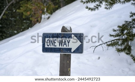 One way road sign on the roads of snow caped mountains. 