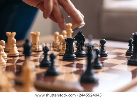 Chess match between friends. Hand of an unrecognizable man picking up one of the white pieces and placing it on the chessboard Royalty-Free Stock Photo #2445524045