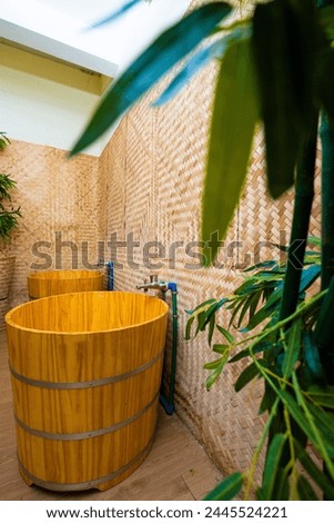 Three wooden tubs with metal hoops sit by a weathered bamboo wall.