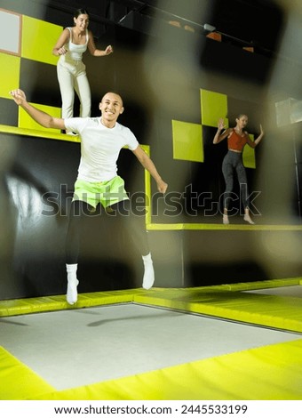 Joyful young man captured in mid-air while jumping on trampolines against backdrop of vivid colorful setting of indoor amusement park.. Royalty-Free Stock Photo #2445533199