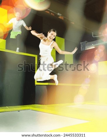 Expressive cheerful young girl enjoying jumping in indoor trampoline arena. Funny active leisure concept ..