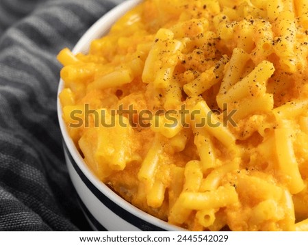 Indulge in homemade macaroni and cheese in a white bowl with blue accents, against a textured grey backdrop. Perfect for culinary bloggers. Royalty-Free Stock Photo #2445542029
