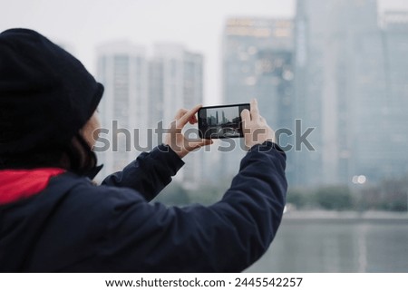 Tourist Capturing City Skyline on Smartphone