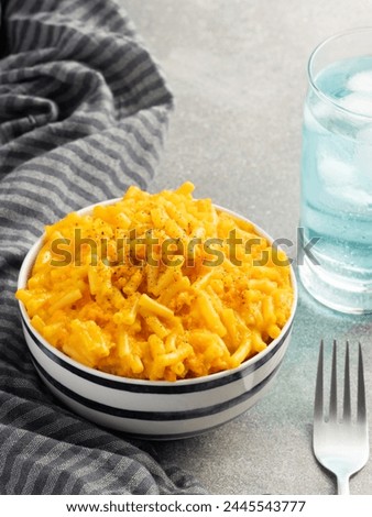 Savor comfort with our stock photo: creamy mac and cheese on a classic cloth, paired with a blue drink against a concrete background. Ideal for food blogs and promotions.