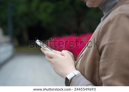 Young Adult Texting on Smartphone in Park