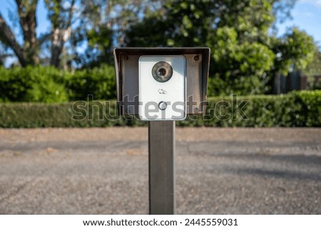A card key reader and intercom with a security camera in the driveway to a corporate parking lot, screening visitors for security and safety.