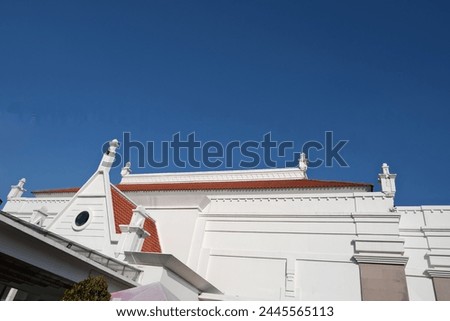Stately white facade with ornate detailing stands proudly under a brilliant blue sky, the essence of neoclassical design
