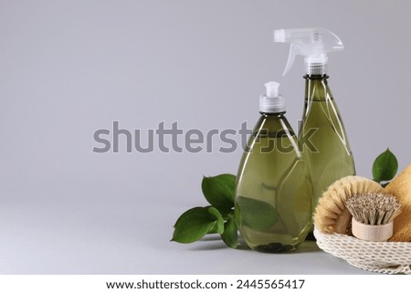 Bottles of cleaning product, brushes and floral decor on light background. Space for text
