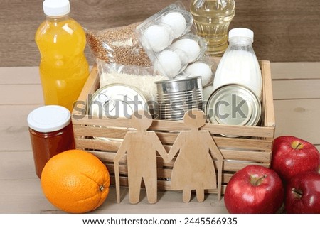 Humanitarian aid for elderly people. Different donation food and figures of senior couple on wooden table