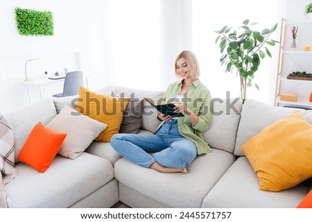 Photo of pretty adorable cute girl sitting on comfy couch reading interesting story enjoy time at home relax rest alone