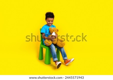 Full size photo of mixed race multiethnic multinational boy wear blue t-shirt hold teddy bear ice cream isolated on yellow background Royalty-Free Stock Photo #2445571943