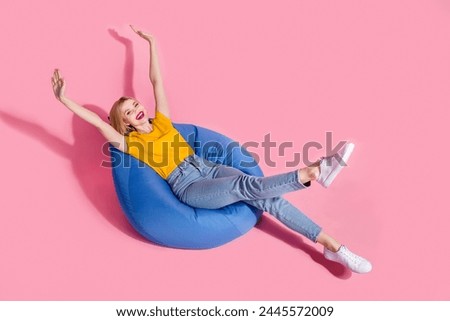 Full length photo of cheerful excited lady dressed yellow t-shirt lying bean bag empty space isolated pink color background