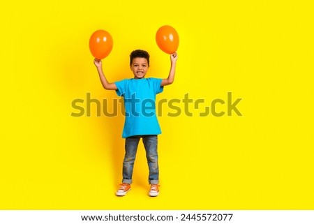 Full size photo of multiethnic multinational boy wear blue t-shirt denim pants raising up balloons isolated on vivid yellow background Royalty-Free Stock Photo #2445572077