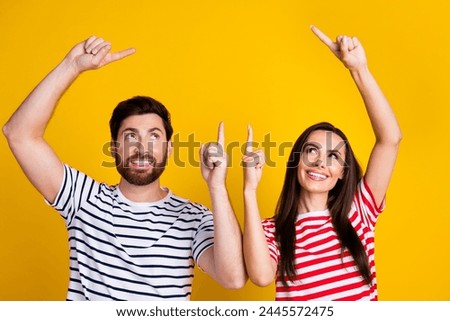 Photo portrait of lovely young couple look point empty space promo wear trendy striped garment isolated on yellow color background