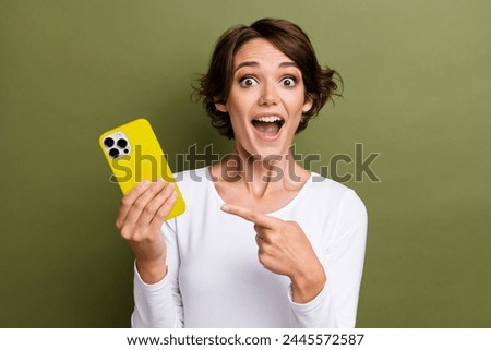Photo portrait of lovely young lady hold point excited device dressed stylish white garment isolated on khaki color background