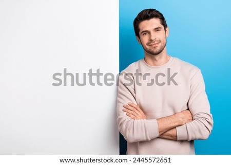 Photo of confident sweet man wear beige sweatshirt arms crossed poster empty space isolated blue color background