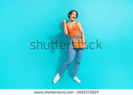 Full size photo of impressed girl dressed knitwear top hold laptop look directing at offer empty space isolated on blue color background
