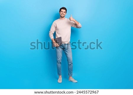 Photo of pleasant handsome cheerful guy dressed white pullover holding laptop showing thumb up nice work isolated on blue color background