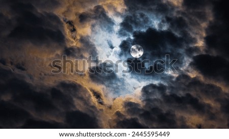 A picture capturing the moon veiled by thick clouds, emitting a soft glow that creates a serene and mysterious ambiance in the night sky