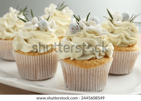Tasty Easter cupcakes with vanilla cream on table, closeup