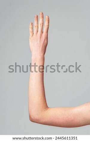 Extended Human Arm Against a Neutral Grey Background Demonstrating Flexibility Royalty-Free Stock Photo #2445611351