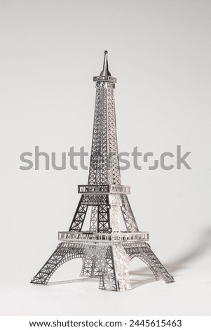 Metal Eiffel Tower cutout on white background. Lattice design highlights skill and precision, creating intricate pattern.