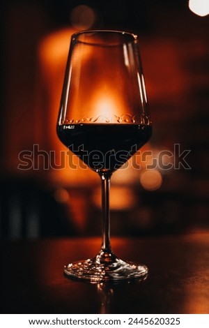 A glass of red wine on a wooden table in the evening bokeh light