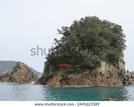 An island with a red torii gate floating in the sea