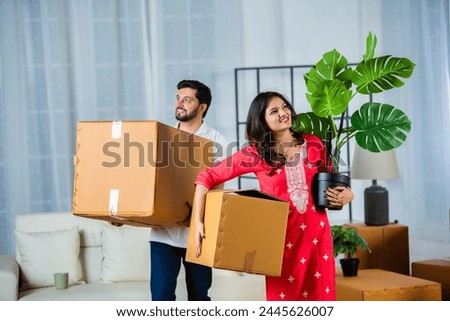 Indian young couple shifting home holding boxes in new home Royalty-Free Stock Photo #2445626007