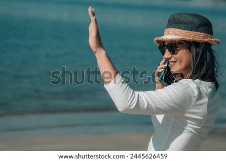 young woman with mobile phone on the beach and say hello