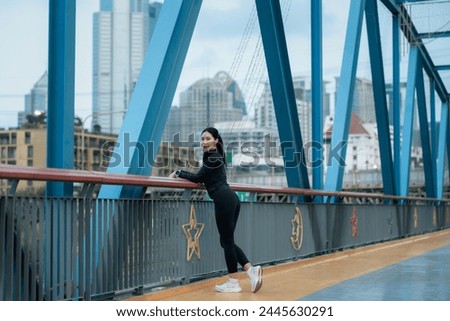 young woman in black sportswear exercise lightly on the bridge in the morning.