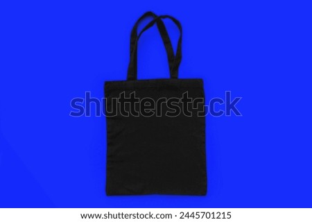Black cotton, canvas, tote, mesh bag on blue background. Zero waste, no plastic, eco friendly shopping, recycling concept. Blank mockup shopper with place for artwork or text. Copy space, flat lay