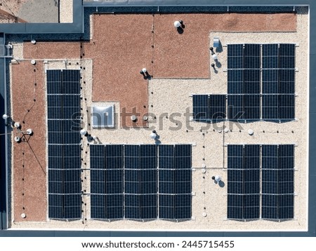 Aerial top down view of new building project with solar panels mounted on the roof using photo-voltaic cells which use sunlight as a source of energy (4K).