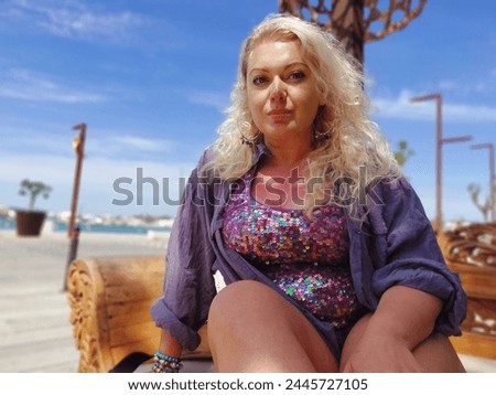 Blonde woman glitter top on holiday beach seafront sitting enjoying vacay vacation  long hair fashion nature leasure holiday dressed up flirty posing model outdoor shoot homemade amateur