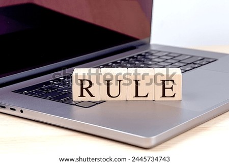 RULE word on a wooden block on laptop , business concept. 