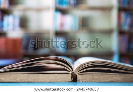 An open book or textbook vintage style on wooden table in the library and the bookshelves background.Education learning concept