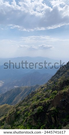 this photo was taken at the highest peaks of al soudah. which are interspersed with brown rocks ,greenplants, and clouds  Royalty-Free Stock Photo #2445741617