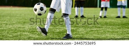 A person passionately kicks a soccer ball on a vibrant field, showcasing skill and determination in a dynamic sports moment. Royalty-Free Stock Photo #2445753695