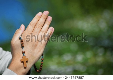 Man praying rosary with folded hands in peaceful nature by the lake Royalty-Free Stock Photo #2445767887