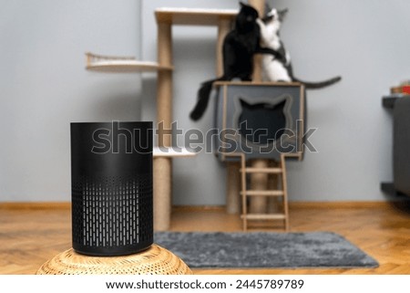 air purifier in the area with pets or cat. Air Pollution Concept. Air purifier, filters out invisible viruses, allergens or pollutants in the house on a cat tree background. Cute cat and Air purifier Royalty-Free Stock Photo #2445789789