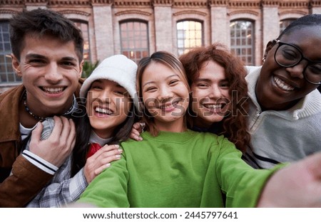 Interracial group of cheerful friends taking selfie together outdoors at university. Diverse people having fun using phone to take photos for social media.