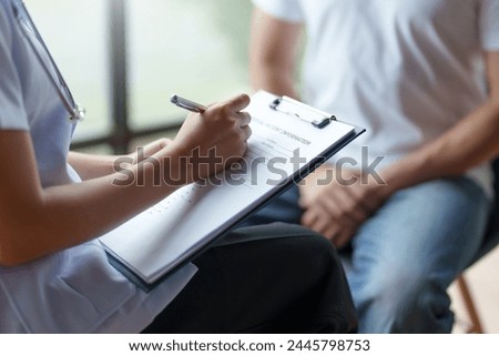 Healthcare professional attentively writing down patient information during a consultation, providing personalized care. Royalty-Free Stock Photo #2445798753