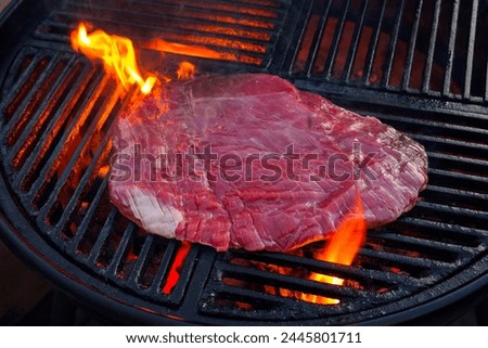 Traditional raw barbecue flanksteak steak as close-up on a charcoal grill with fire  Royalty-Free Stock Photo #2445801711